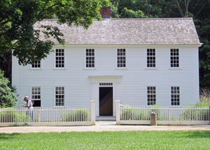 The parsonage is on the green. Notice the unpaved street and the absence of a concrete curb. 